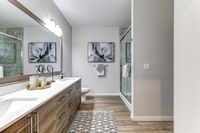 Elegant modern bathroom with a sleek double vanity, large mirror, and spacious glass shower.