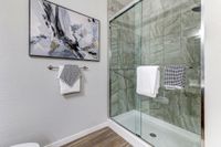 Elegant bathroom featuring a sleek, glass-enclosed shower with modern tile design, complemented by contemporary artwork and fresh towels for a luxurious touch.
