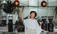 woman taking selfie in front of coffee makers in coffee shop