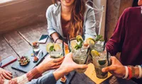 people toasting with drinks in hand at restaurant over appetizers