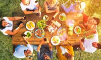 group of people around table eating meal outdoors