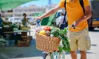 man holding up bicycle with vegetables in front basket