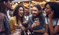 four people with drinks and dog outside