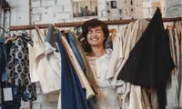 woman peeking out of clothing rack