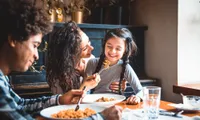 woman feeds child while man eats at same table at restaurant
