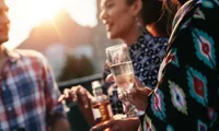 people standing with drinks in hand outdoors at dusk