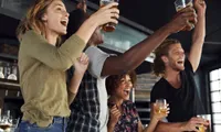 people toasting with drinks in hand at resturant bar