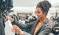 woman looking at blouse in boutique store