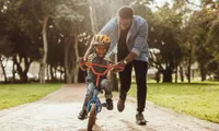 man with child on bicycle in park in daytime