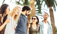 group of friends walking on the beach with palm tree in back ground
