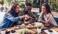 three friends eating outdoors smiling at phone