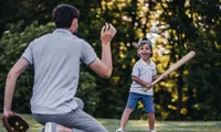 Dad playing ball with son in a park