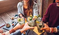 Group of friends toasting with refreshing mojitos at a rustic table setting.