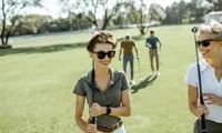 Smiling group of four golfers enjoying a sunny day on the course.