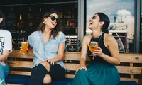 two women drinking beer outside smiling