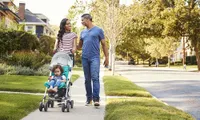 Mom and dad with kid in stroller walking down sidewalk