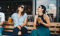Two women laughing over beer