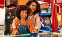 mom and kid playing air hockey at an arcade bar