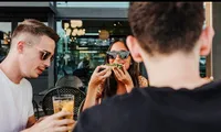 girl eating pizza with two guys at a restaurant