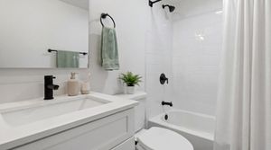 Modern bathroom with sleek white vanity, stylish black fixtures, and elegant shower area.