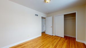 Bright and inviting room with polished wood flooring, a built-in closet, and classic white doors.