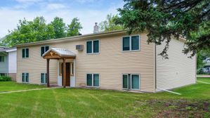 Charming suburban home with beige siding, lush green lawn, and mature trees creating a peaceful atmosphere.