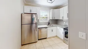 Modern kitchen with stainless steel appliances, white cabinetry, and granite countertops.