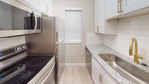 Modern kitchen featuring sleek stainless steel appliances, granite countertops, and white cabinetry.