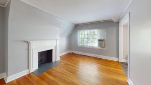 Inviting living room featuring a classic white fireplace and a large window with natural light.