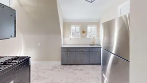 Contemporary kitchen with stainless steel appliances, sleek grey cabinetry, and marble tile flooring.