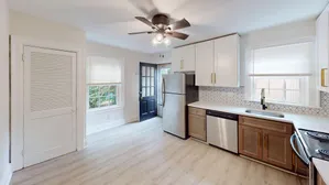 Bright and modern kitchen with sleek stainless steel appliances, white cabinetry, and a geometric backsplash design.
