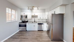 Modern kitchen with sleek stainless steel appliances, bright white cabinetry, and elegant granite countertops.