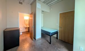 Bright bedroom with cozy bed, minimalist furniture, and en-suite bathroom in a modern apartment.