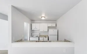 Modern kitchen with sleek white cabinets, granite countertops, and stainless steel sink, offering a bright and open design.
