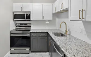 Contemporary kitchen with granite countertops, white cabinets, and stainless steel appliances.