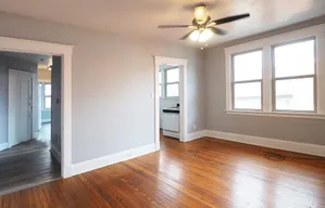 Inviting living space with warm hardwood floors, abundant natural light from large windows, and a stylish ceiling fan for modern comfort.
