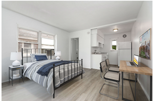 Bright studio apartment with a comfortable bed, modern kitchenette, and a sleek work desk.
