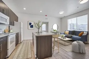 Modern open-concept living space with sleek kitchen, stylish island seating, and cozy lounge area filled with natural light.