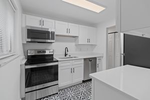 Sleek modern kitchen featuring white cabinetry, stainless steel appliances, and elegant patterned flooring.