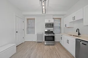 Bright modern kitchen with sleek stainless steel appliances, elegant cabinetry, and stylish light fixture, offering a welcoming and functional cooking space.