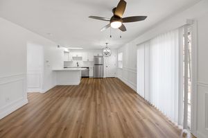 Modern open-concept living area with stylish ceiling fan, hardwood floors, and sleek kitchen featuring stainless steel appliances.