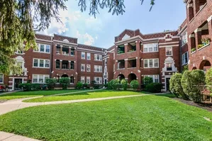 Charming red brick apartment complex with lush green lawn and classic architectural details, perfect for serene living.