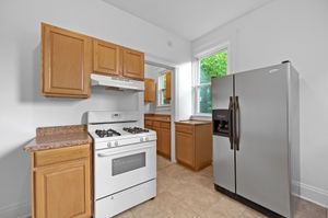 Modern kitchen with sleek stainless steel refrigerator, gas stove, and natural wood cabinetry, offering a bright and functional space.