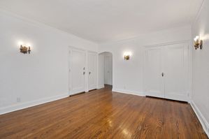 Elegant living space with polished wooden floors and classic white doors, enhanced by warm wall sconces for a cozy atmosphere.