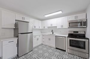 Modern kitchen with stainless steel appliances, elegant white cabinetry, and intricate patterned flooring.