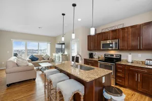 Modern open-concept living area with elegant granite countertops, stylish kitchen, and cozy seating, boasting stunning city views through large windows.