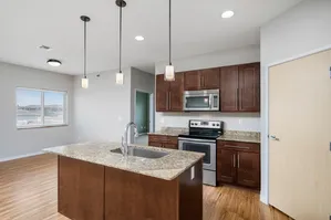 Modern kitchen design with granite countertops, stainless steel appliances, and elegant pendant lighting in a bright and spacious open layout.