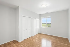 Bright, spacious bedroom with elegant wood flooring, large windows offering scenic views, and ample closet space.