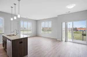 Bright, modern open-concept living space with hardwood floors, a stylish kitchen island, and large windows offering an inviting view.