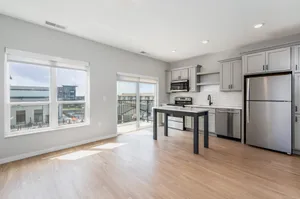 Bright and modern open-concept kitchen with stainless steel appliances, sleek cabinetry, and large windows offering sunny views.